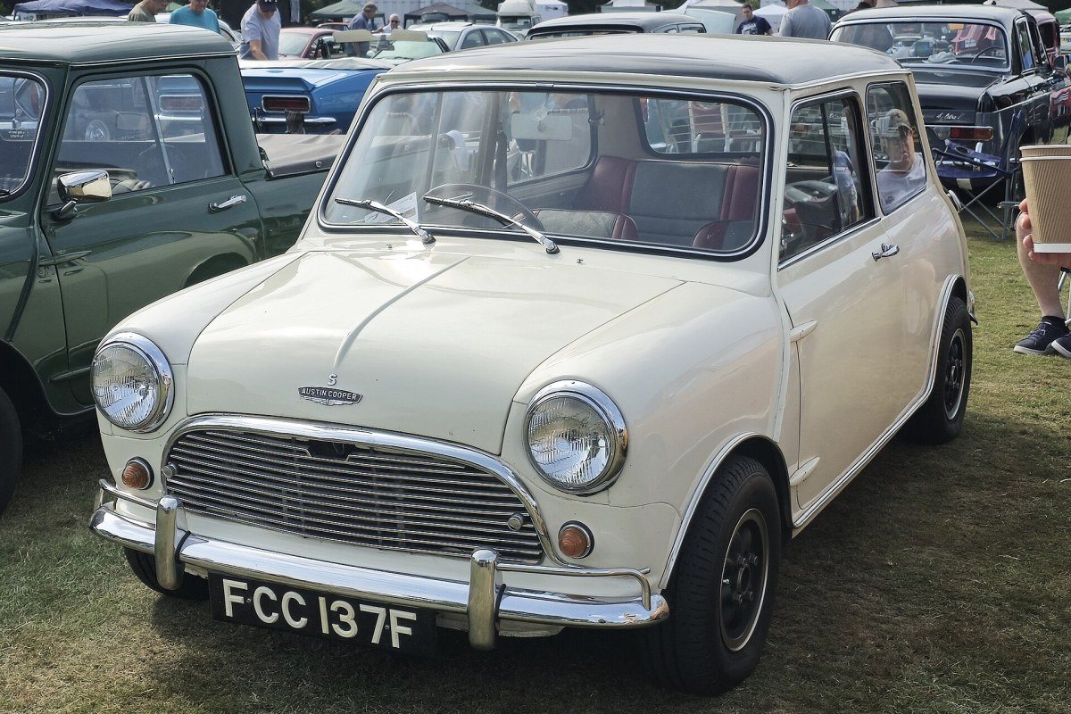 A small classic Mini car with round headlights parked on a street.