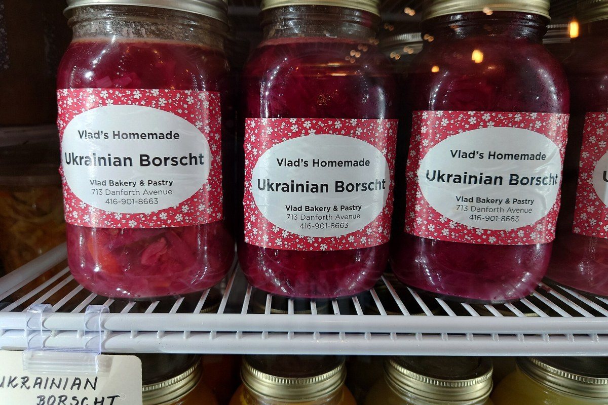 A bowl of red Ukrainian borscht served with sour cream and bread.