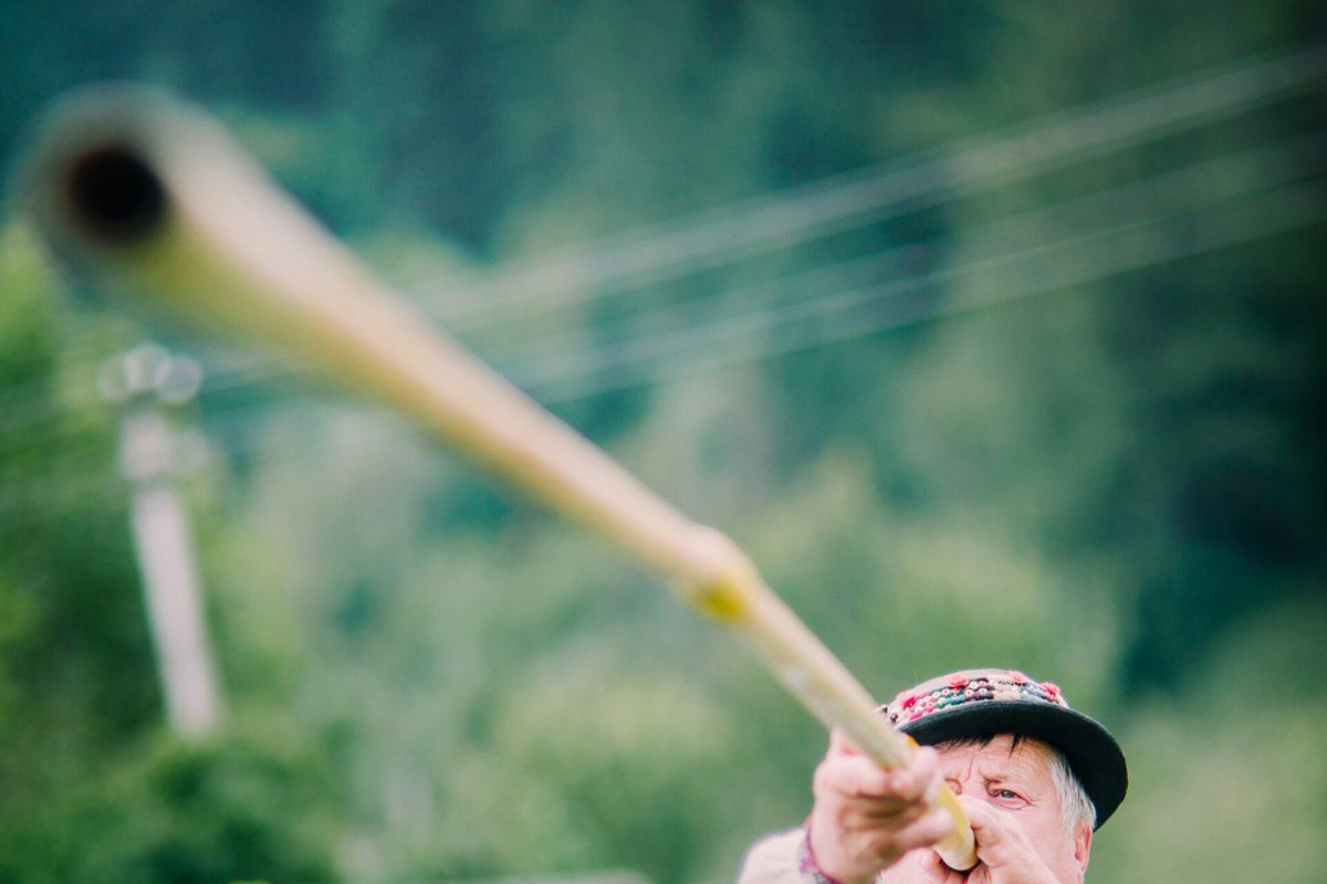 A Hutsul musician playing a long wooden trembita horn in the Carpathian mountains.