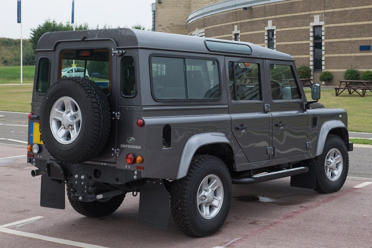 A classic Land Rover Defender off-road vehicle on a rough track.