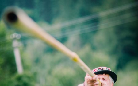 A Hutsul musician playing a long wooden trembita horn in the Carpathian mountains.