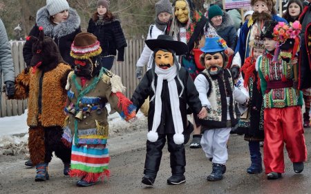 Costumed participants of the Malanka folk carnival walking through a snowy street in Bukovina.