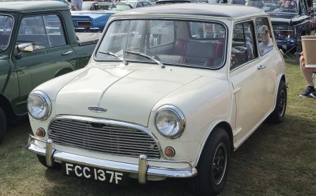 A small classic Mini car with round headlights parked on a street.