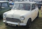A small classic Mini car with round headlights parked on a street.