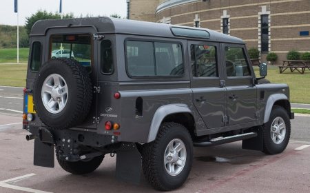 A classic Land Rover Defender off-road vehicle on a rough track.